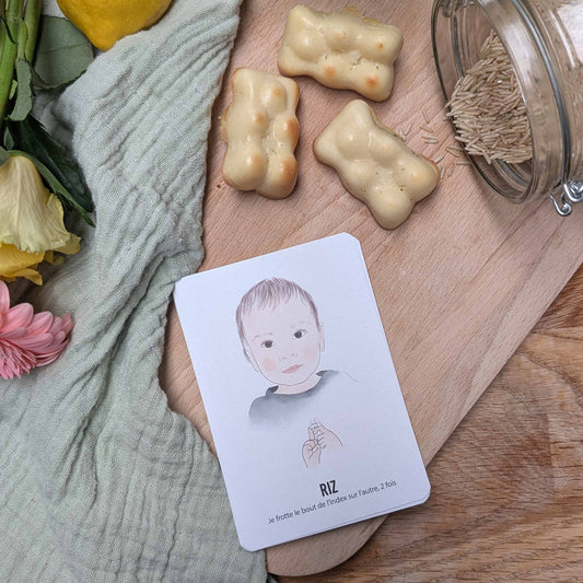 carte bébé signe riz mise en scène sur une table dressée avec des fleurs et des petits gateaux