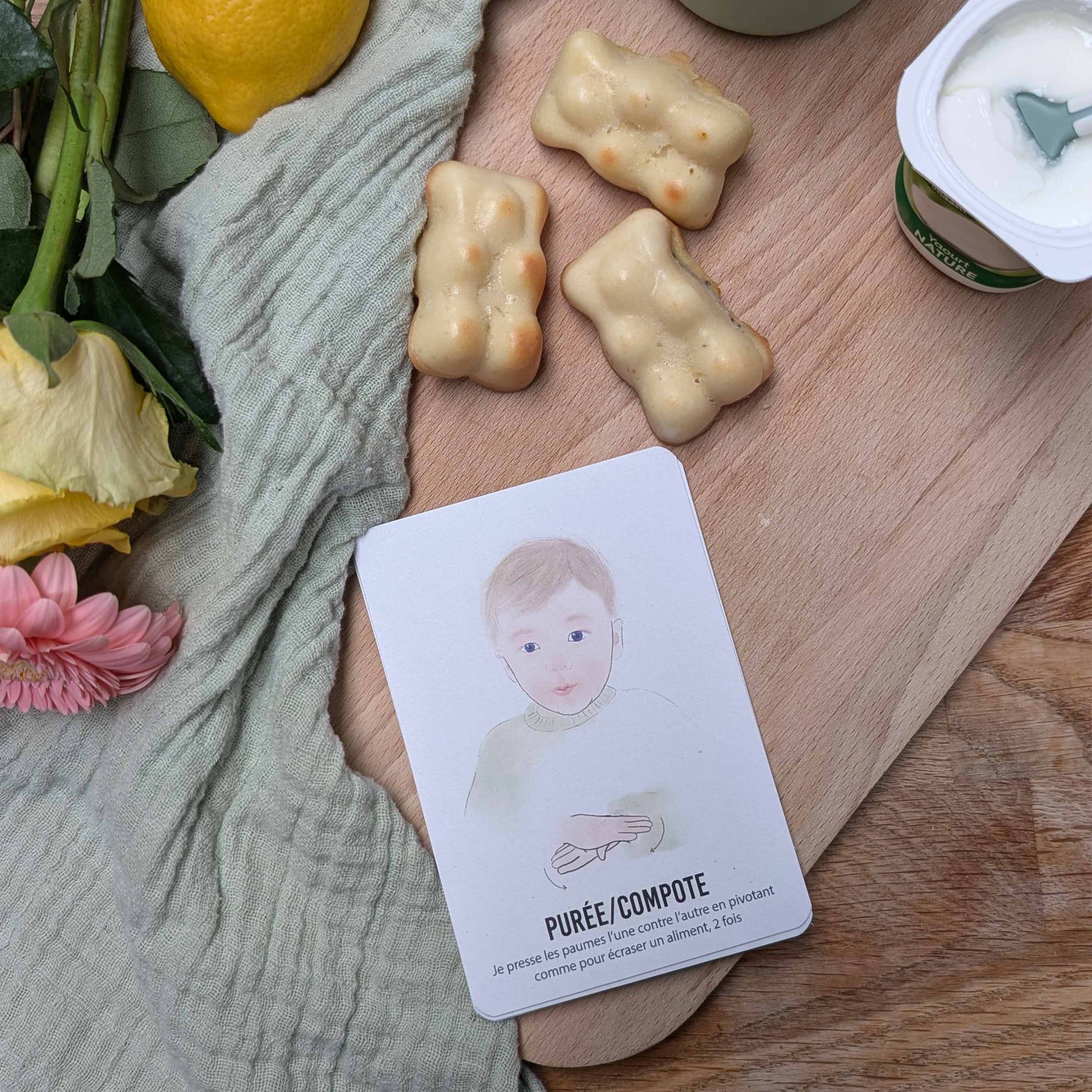 Signer avec bébé carte purée mise en scène sur une table en bois avec un yaourt et des petits gateaux en forme d'ourson