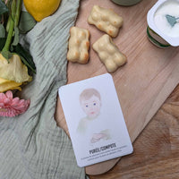 Signer avec bébé carte purée mise en scène sur une table en bois avec un yaourt et des petits gateaux en forme d'ourson