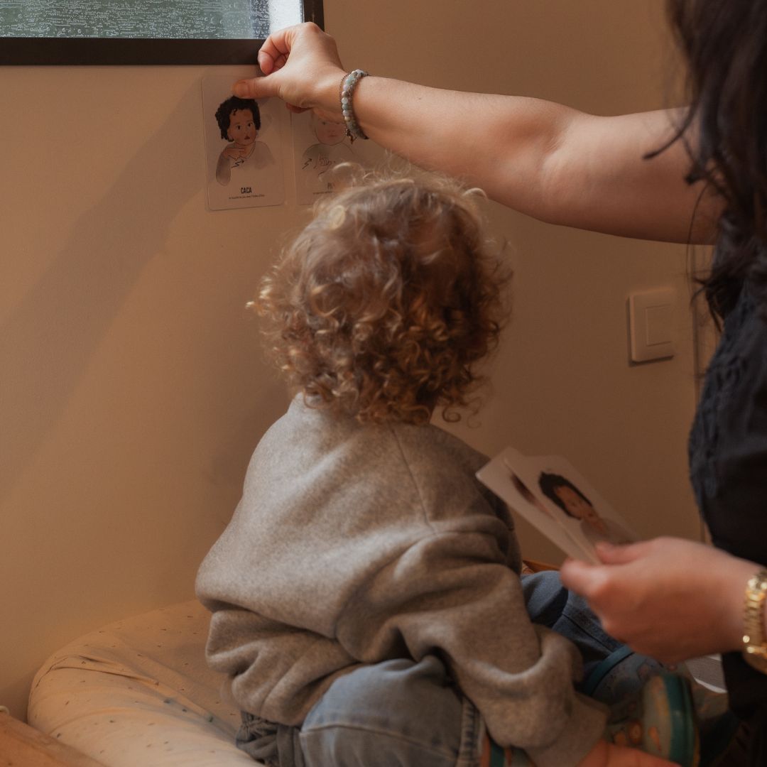 maman et bébé installent les cartes bébé signe au dessus de la table à langer