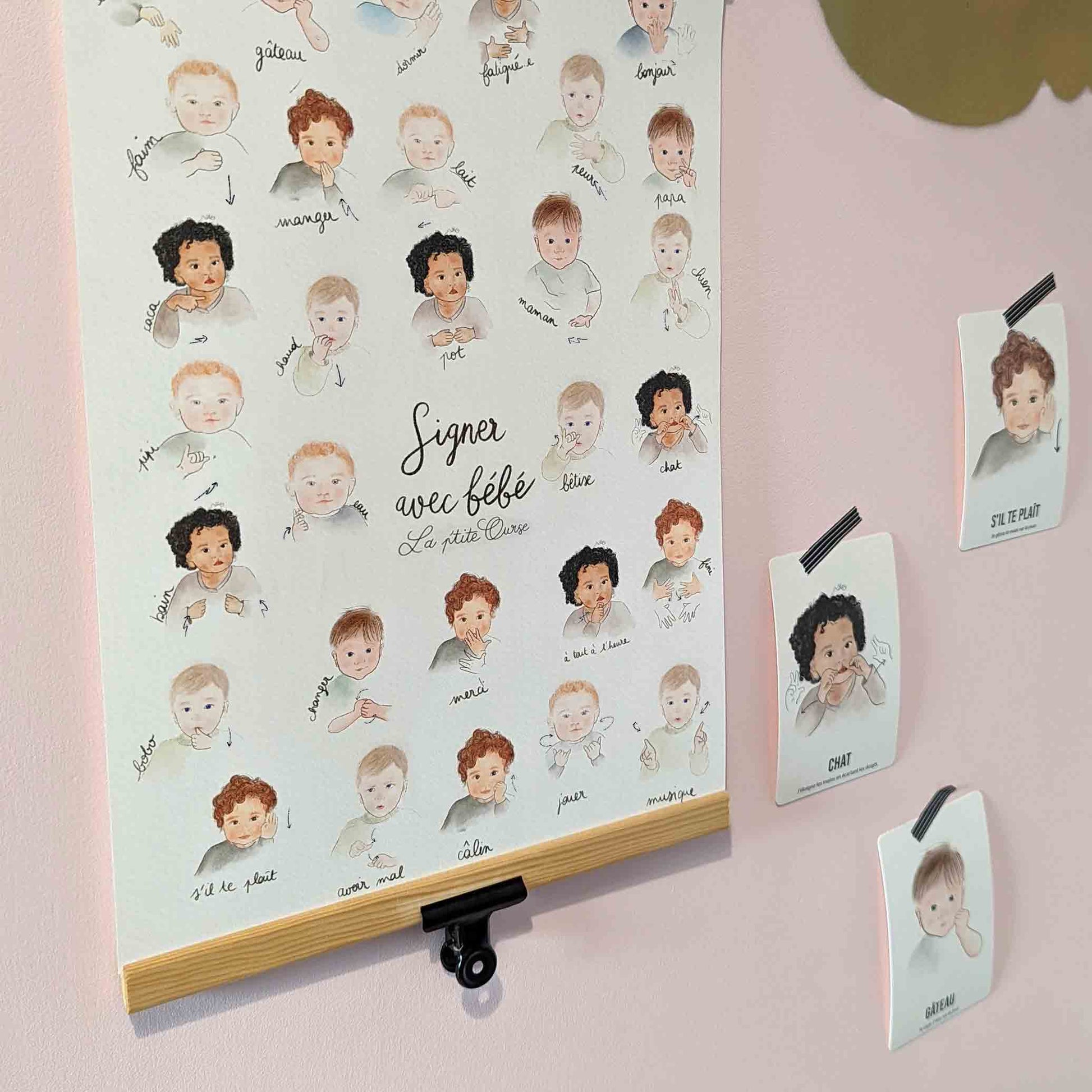 Affiche signer avec bébé installée dans la chambre d'enfant avec des cartes bébé signe accrochés au mur grâce à du masking tape noir et blanc