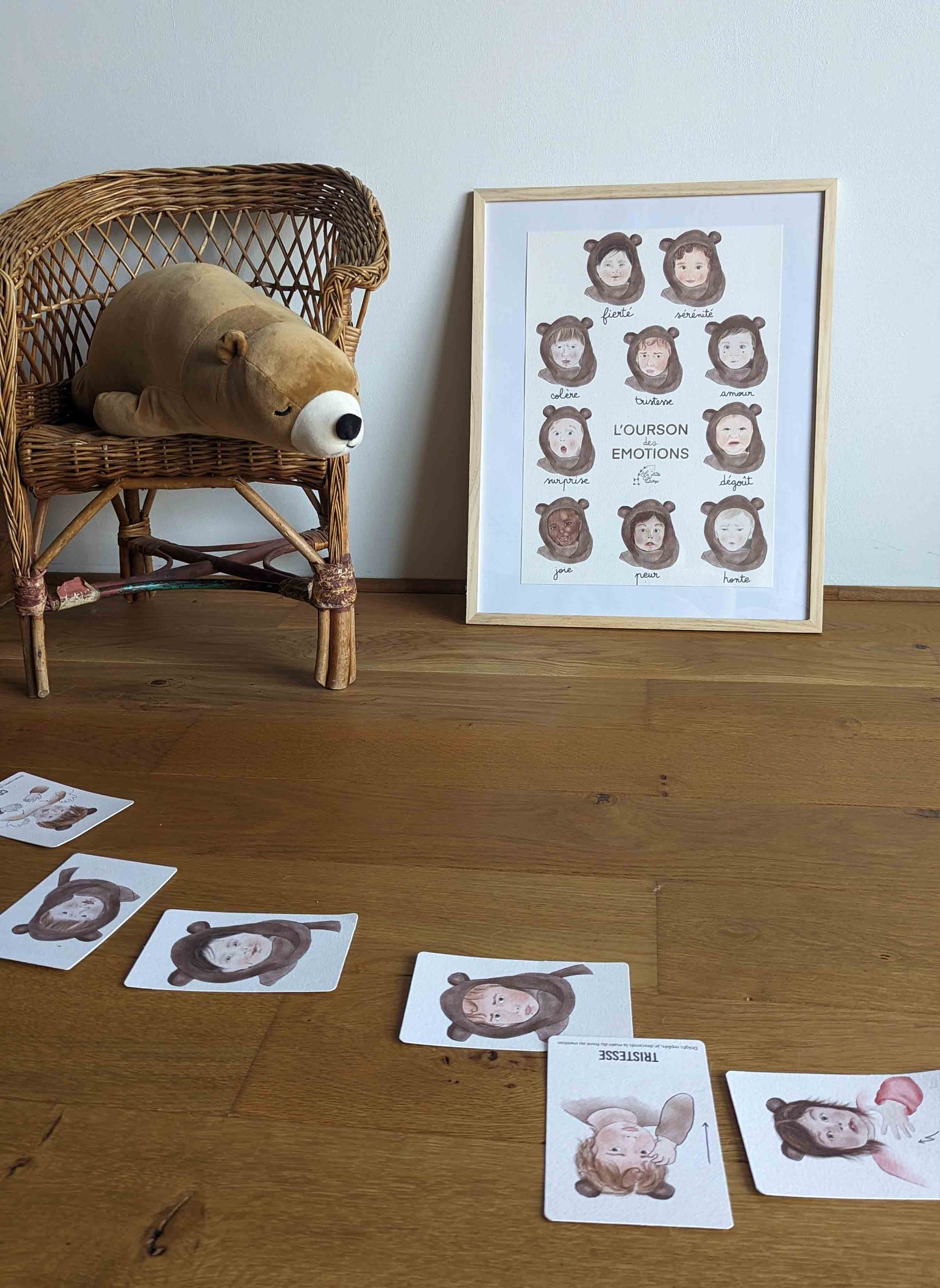 Affiche et cartes bébé signe, l'Ourson des Émotions mises en scène au sol, avec une peluche d'ours regardant la scéne.