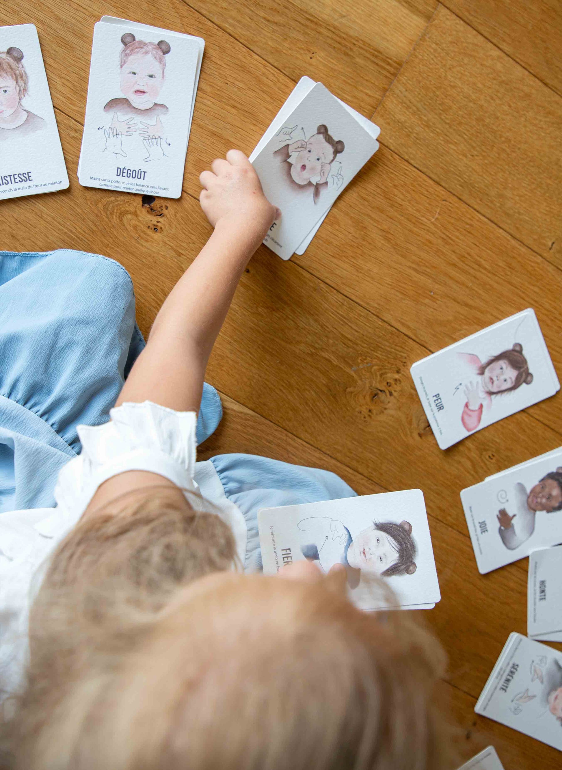 Enfant jouant avec les cartes "Signer avec Bébé" sur le sol.