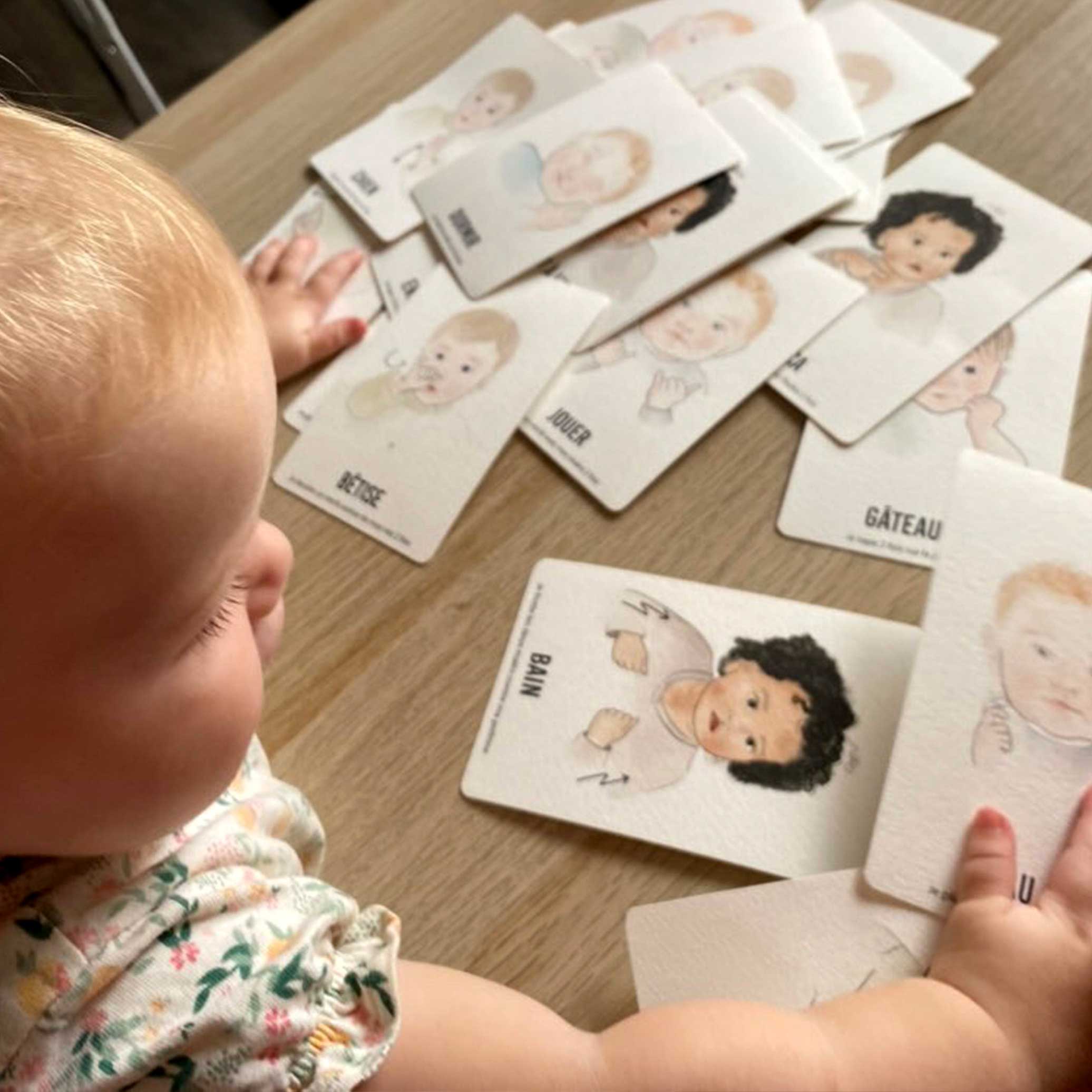 Amélia découvre les cartes bébé signe sur la table